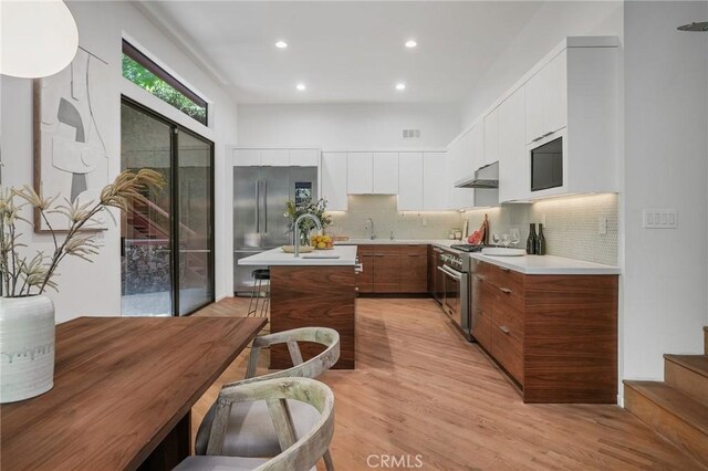 kitchen featuring white cabinetry, a center island, light hardwood / wood-style flooring, backsplash, and high end appliances