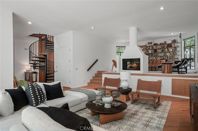 living area featuring wood finished floors, stairway, a multi sided fireplace, and recessed lighting