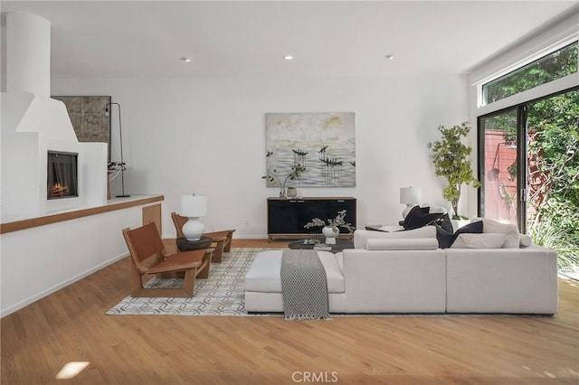 living area with recessed lighting, a fireplace, baseboards, and wood finished floors