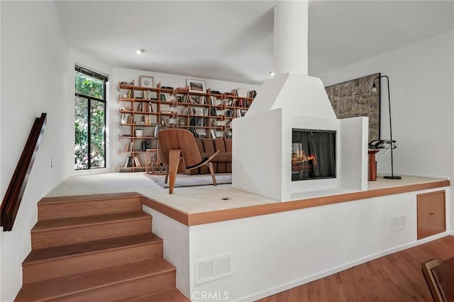 unfurnished room featuring a multi sided fireplace and hardwood / wood-style flooring