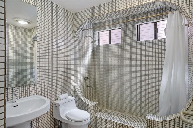 bathroom featuring toilet, sink, tile walls, and walk in shower