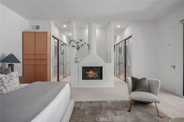 bedroom featuring light carpet and a large fireplace