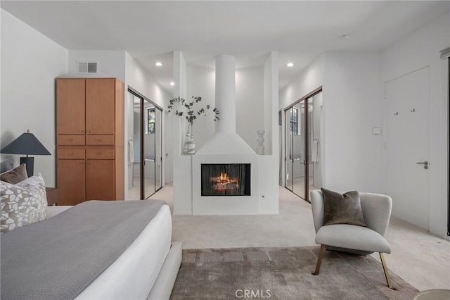 bedroom with a lit fireplace, recessed lighting, visible vents, and light colored carpet