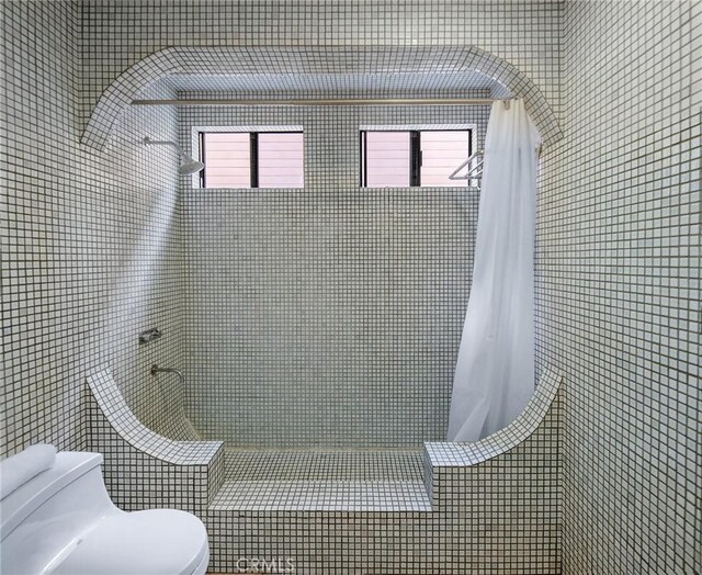 bathroom featuring plenty of natural light, curtained shower, toilet, and tile walls