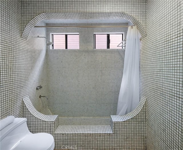 bathroom featuring tiled shower, tile walls, and toilet