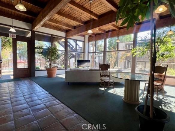 unfurnished sunroom featuring wood ceiling, beam ceiling, and plenty of natural light