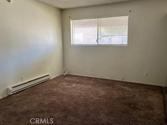 spare room featuring a baseboard radiator, a textured ceiling, and dark carpet