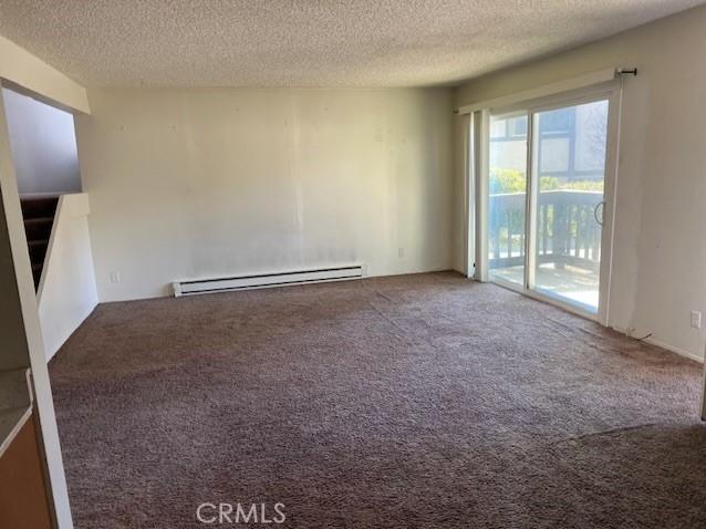 unfurnished room with carpet, a textured ceiling, and baseboard heating