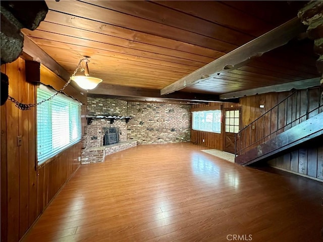 unfurnished living room with wood walls, wood-type flooring, and brick wall