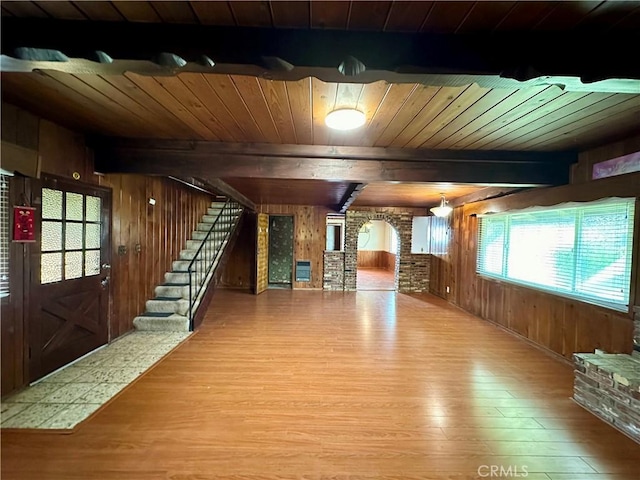 unfurnished living room with beamed ceiling, hardwood / wood-style floors, wooden ceiling, and wood walls