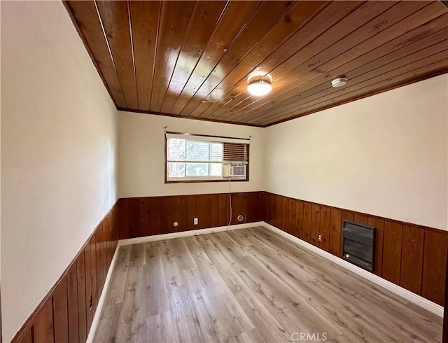 empty room featuring ornamental molding, light hardwood / wood-style flooring, wooden walls, and wood ceiling