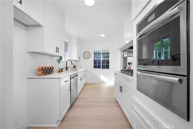 kitchen featuring white cabinets, stainless steel appliances, and a wealth of natural light