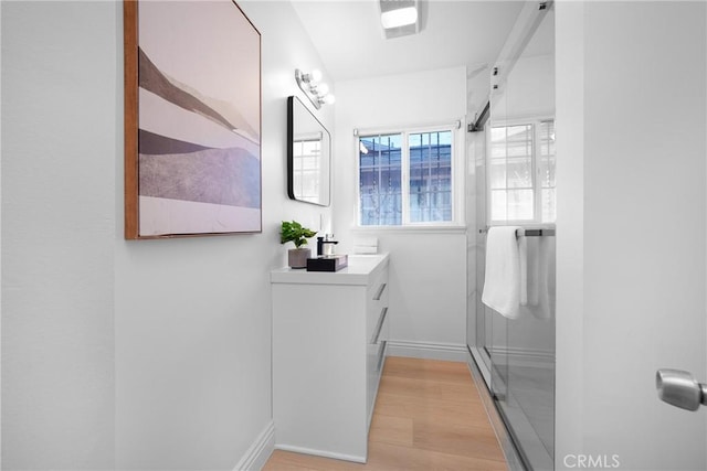 bathroom with vanity, an enclosed shower, and hardwood / wood-style flooring