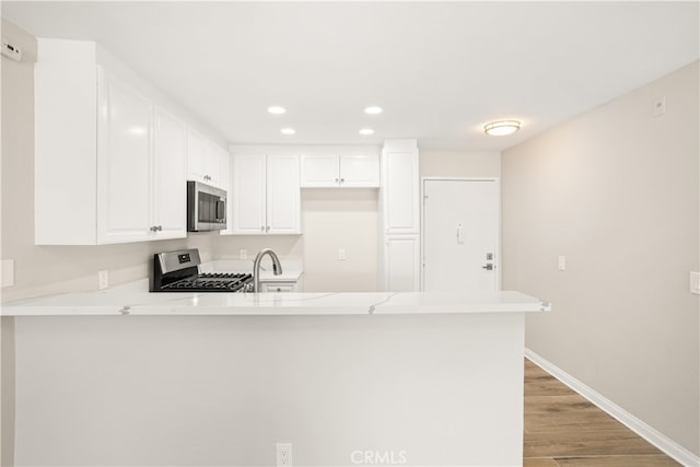 kitchen featuring appliances with stainless steel finishes, kitchen peninsula, and white cabinets