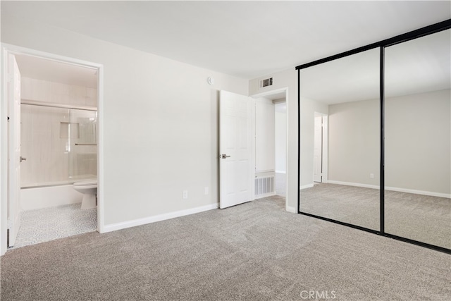 unfurnished bedroom with a closet, carpet flooring, and connected bathroom