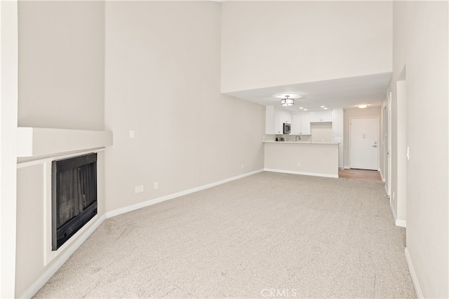 unfurnished living room featuring sink and light colored carpet