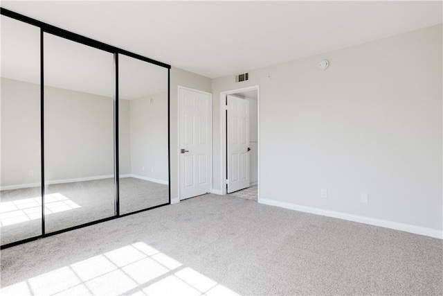 unfurnished bedroom featuring light carpet and a closet