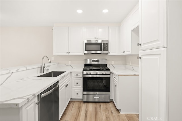 kitchen featuring light stone counters, white cabinetry, light hardwood / wood-style flooring, sink, and stainless steel appliances