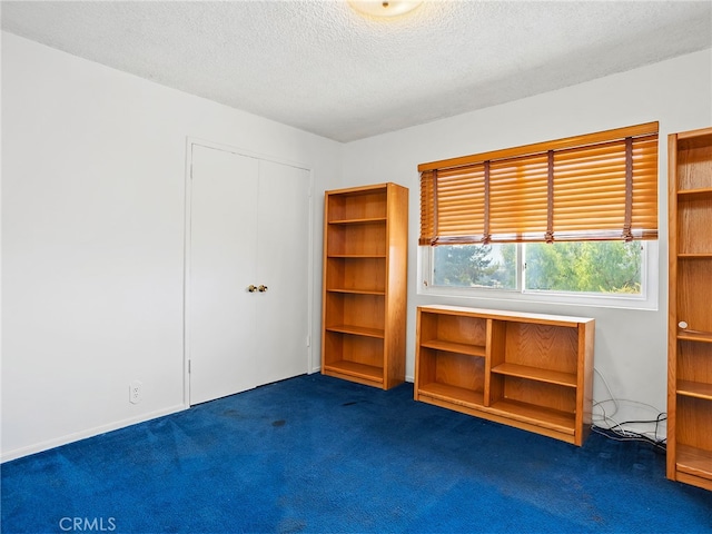 interior space featuring a closet, a textured ceiling, and dark carpet