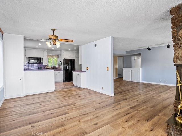 kitchen with black appliances, white cabinets, a textured ceiling, and light wood-type flooring