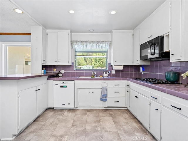 kitchen with tile counters, white cabinets, black appliances, and backsplash