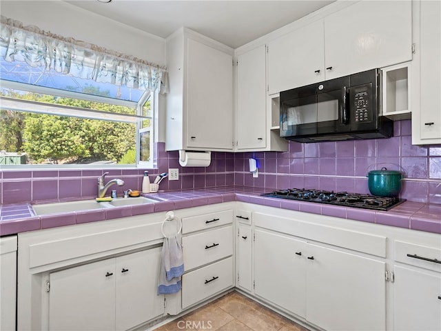 kitchen with tile countertops, black appliances, light tile patterned floors, white cabinets, and tasteful backsplash