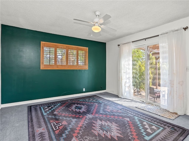 interior space with a textured ceiling, carpet, and ceiling fan