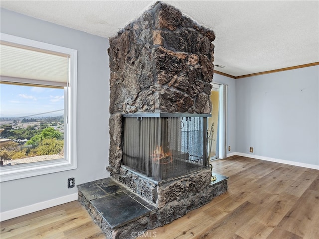 living room featuring ornamental molding, a multi sided fireplace, hardwood / wood-style floors, and a textured ceiling