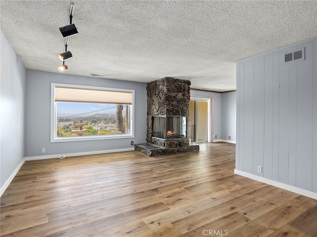 unfurnished living room featuring light hardwood / wood-style floors, a textured ceiling, and a fireplace