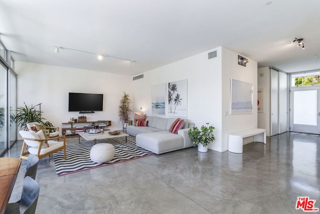 living room featuring concrete flooring, rail lighting, and floor to ceiling windows