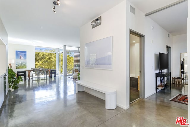 corridor with floor to ceiling windows and concrete floors