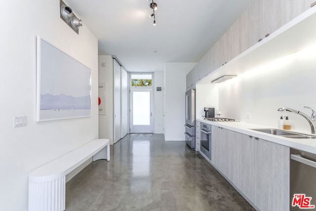 kitchen with light brown cabinetry, stainless steel appliances, and sink