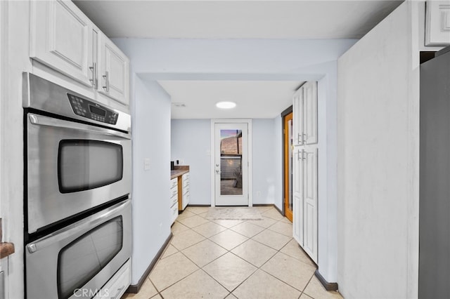 kitchen with white cabinets, light tile patterned flooring, and stainless steel appliances