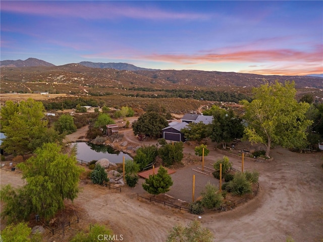 aerial view at dusk featuring a water and mountain view