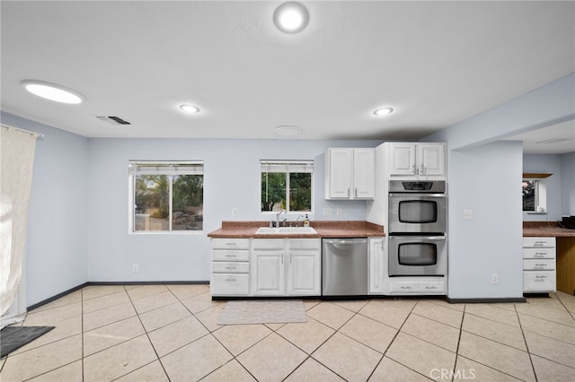 kitchen featuring white cabinets, appliances with stainless steel finishes, light tile patterned flooring, and sink