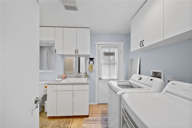 laundry room with washing machine and dryer, sink, light tile patterned floors, and cabinets