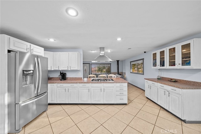 kitchen with kitchen peninsula, white cabinets, wall chimney range hood, and appliances with stainless steel finishes