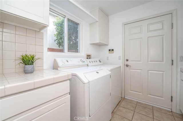 laundry area featuring light tile patterned flooring, cabinets, and washing machine and dryer