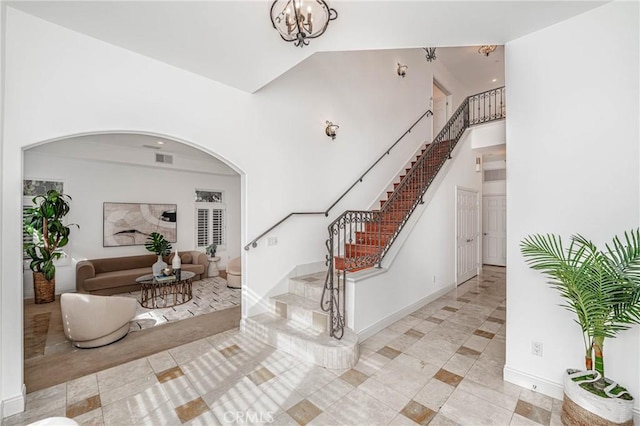 foyer featuring light tile patterned flooring, a towering ceiling, and a chandelier