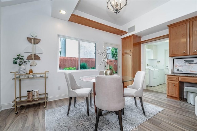 dining space with a chandelier, washer and dryer, and light wood-type flooring