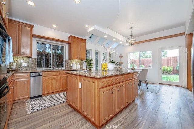 kitchen featuring decorative backsplash, a center island with sink, light hardwood / wood-style floors, and decorative light fixtures