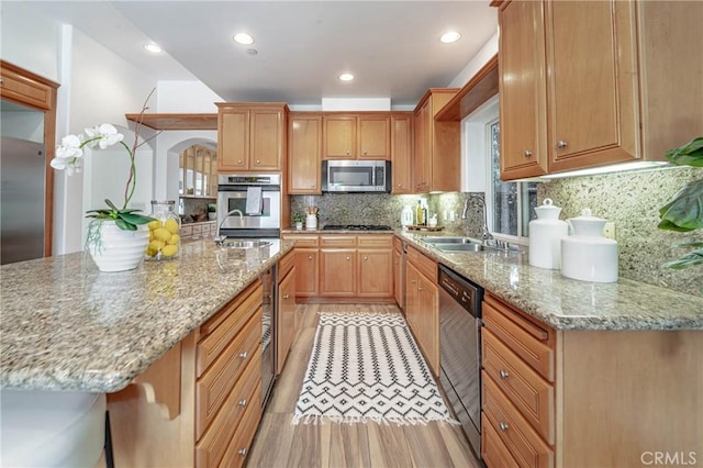 kitchen featuring sink, light stone countertops, stainless steel appliances, and tasteful backsplash