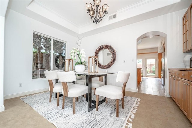 dining space with a notable chandelier, crown molding, and a tray ceiling