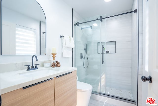 bathroom with an enclosed shower, vanity, and toilet