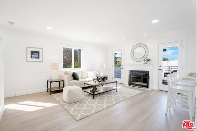 living room with plenty of natural light, light wood-type flooring, and ornamental molding