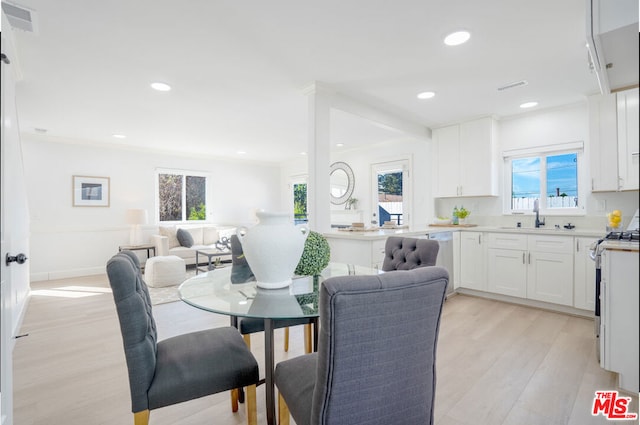 dining area featuring light hardwood / wood-style floors, ornamental molding, and sink