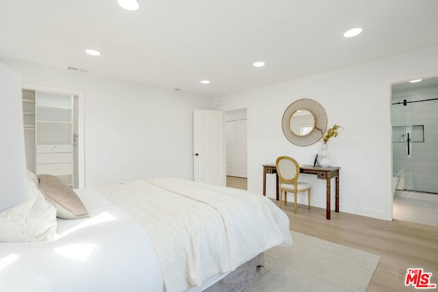 bedroom with connected bathroom and light wood-type flooring