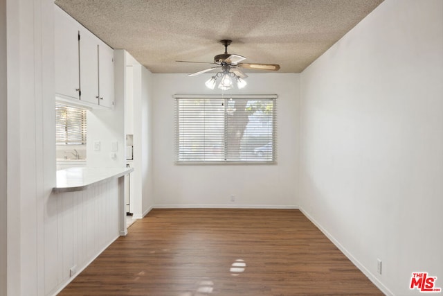 unfurnished dining area with a textured ceiling, dark hardwood / wood-style flooring, and a healthy amount of sunlight