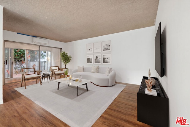 living room featuring a wall mounted air conditioner, a textured ceiling, and hardwood / wood-style flooring