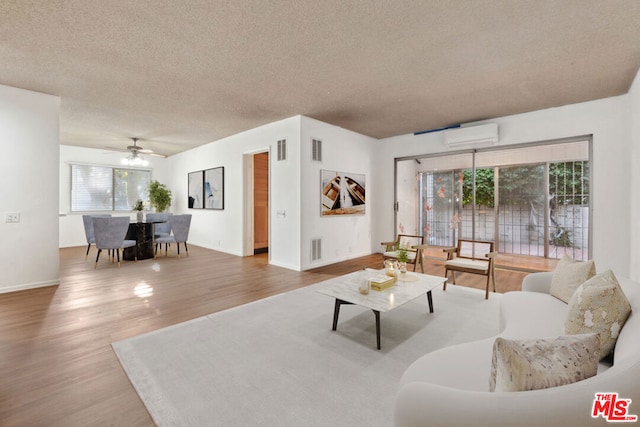 living room with ceiling fan, hardwood / wood-style floors, a healthy amount of sunlight, and a textured ceiling